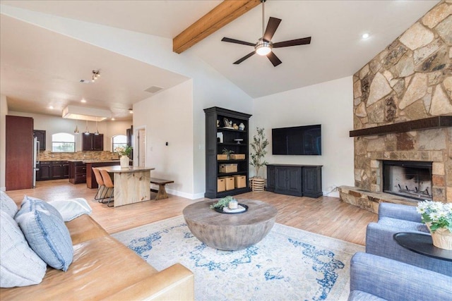 living room featuring a ceiling fan, visible vents, a fireplace, lofted ceiling with beams, and light wood-style flooring