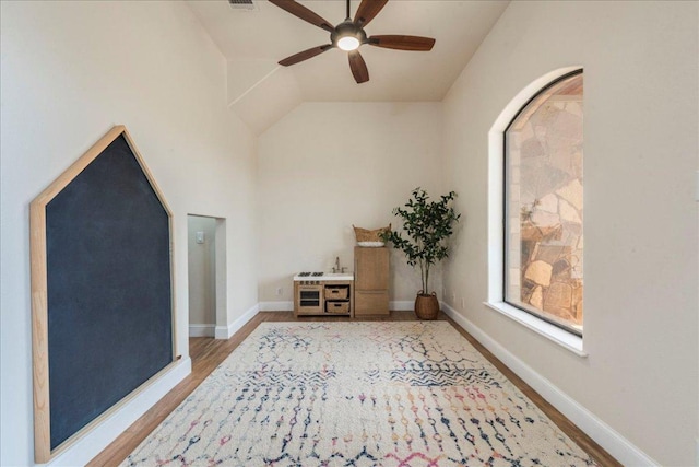 interior space featuring baseboards, ceiling fan, light wood-type flooring, and lofted ceiling