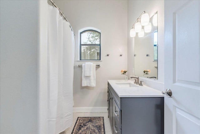 full bath featuring vanity, tile patterned flooring, and baseboards