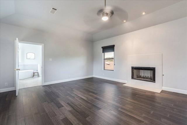 unfurnished living room with visible vents, a fireplace, ceiling fan, dark wood-style floors, and vaulted ceiling