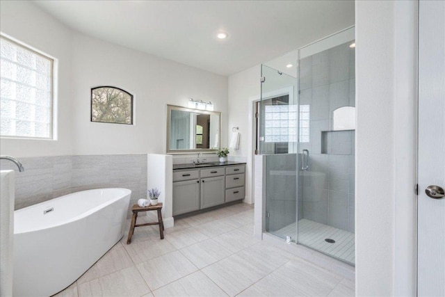 full bathroom featuring a freestanding tub, vanity, tile patterned flooring, and a shower stall