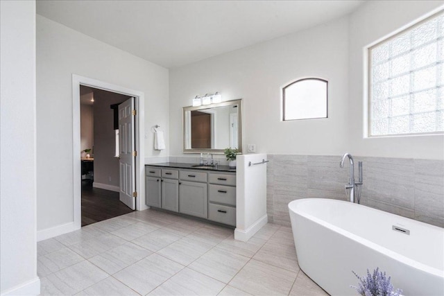 bathroom featuring a freestanding tub, tile patterned flooring, tile walls, wainscoting, and vanity