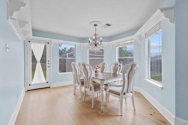 dining area featuring visible vents, light wood-style flooring, baseboards, and a notable chandelier
