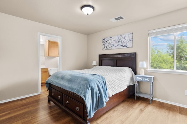 bedroom featuring visible vents, baseboards, and wood finished floors