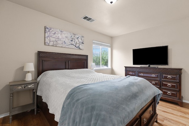 bedroom with baseboards, wood finished floors, and visible vents