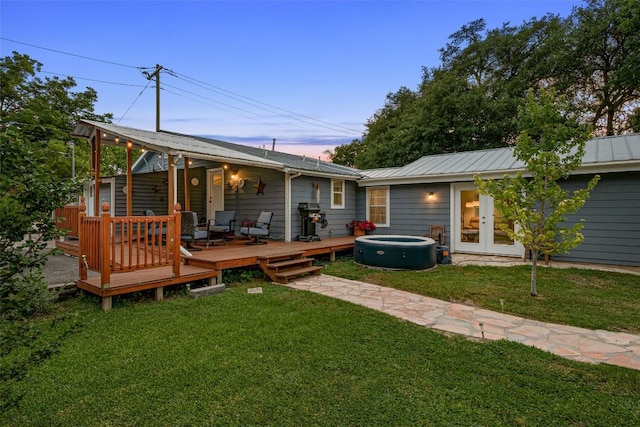 120 Highland Ln, Kingsland, TX 78639 - back of house at dusk with a lawn, a wooden deck, a metal roof, french doors, and a standing seam roof