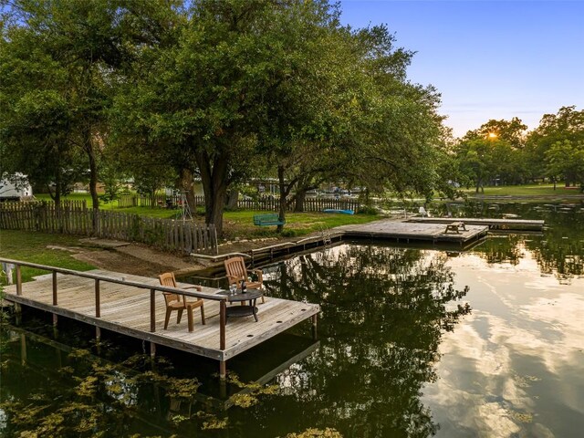 view of dock with a water view and fence