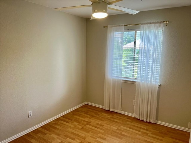 spare room with baseboards, light wood-style flooring, and ceiling fan