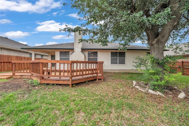 rear view of property with roof with shingles, fence, a yard, and a wooden deck