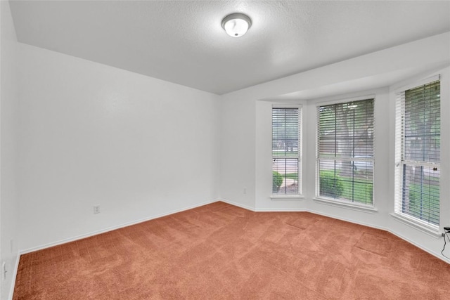 spare room with carpet floors, a textured ceiling, and baseboards