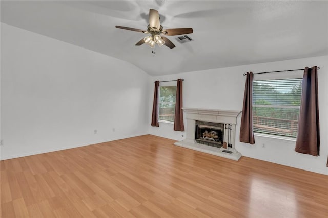 unfurnished living room featuring ceiling fan, visible vents, a fireplace with raised hearth, lofted ceiling, and light wood-style floors