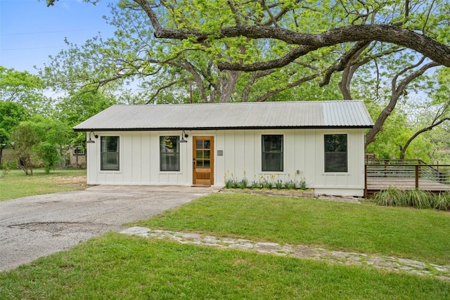 view of front facade featuring aphalt driveway, board and batten siding, and a front yard