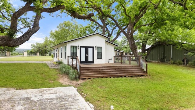 rear view of house with fence, a deck, french doors, central AC unit, and a yard