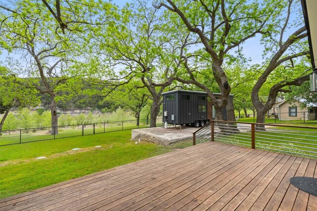 wooden terrace with a lawn, an outdoor structure, and fence
