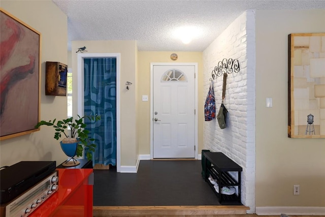 foyer entrance with baseboards and a textured ceiling