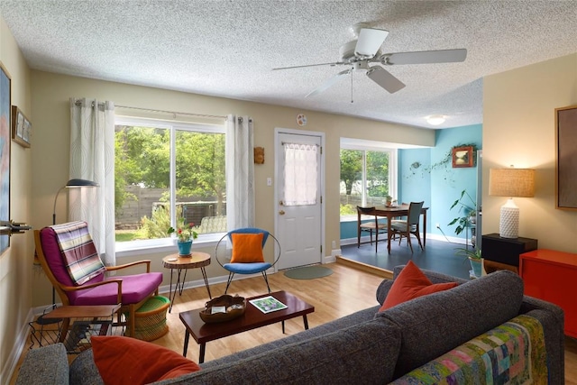 living room featuring baseboards, a textured ceiling, ceiling fan, and wood finished floors