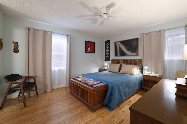bedroom with a ceiling fan, a textured ceiling, and light wood-style flooring