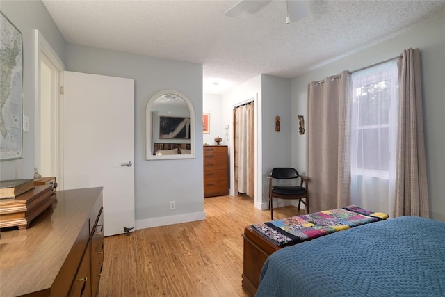 bedroom featuring baseboards, ceiling fan, light wood-type flooring, and a textured ceiling