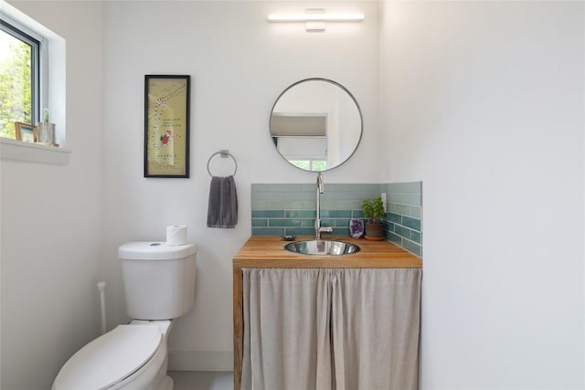 half bathroom featuring toilet, a sink, and tasteful backsplash