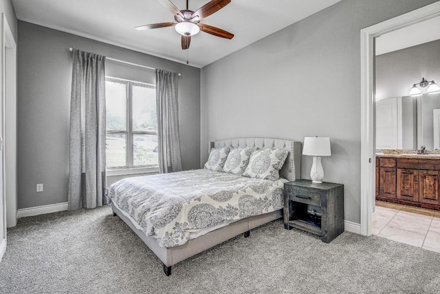 carpeted bedroom with baseboards, a sink, ceiling fan, and ensuite bath