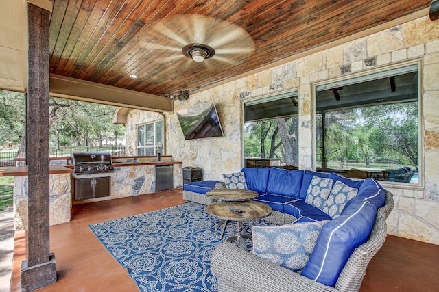 view of patio with outdoor lounge area, fence, grilling area, a ceiling fan, and exterior kitchen