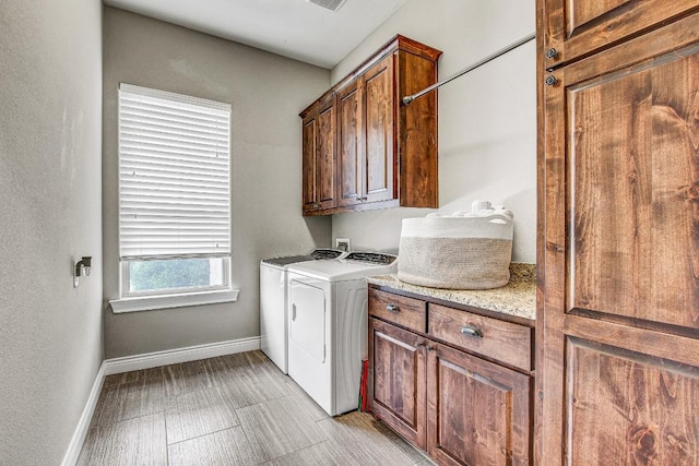 washroom featuring cabinet space, baseboards, and washing machine and dryer
