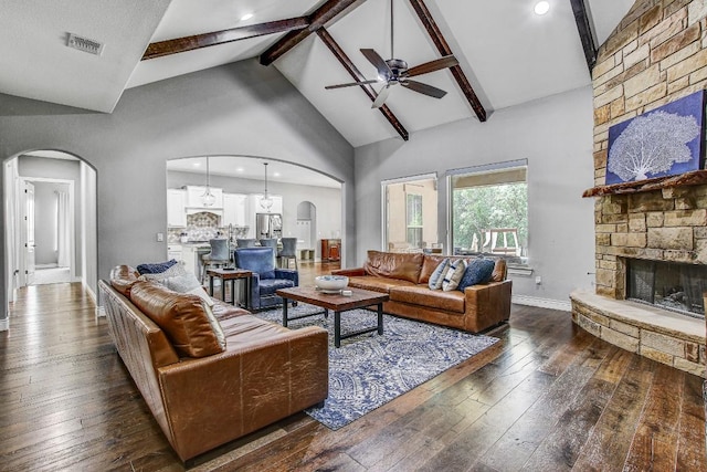 living area featuring visible vents, arched walkways, ceiling fan, and a stone fireplace