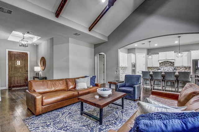 living room featuring arched walkways, dark wood finished floors, and visible vents