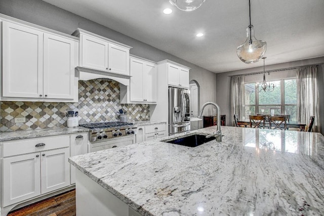 kitchen with backsplash, appliances with stainless steel finishes, a sink, white cabinets, and recessed lighting