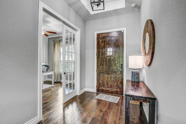 entryway featuring baseboards, a textured wall, and hardwood / wood-style flooring