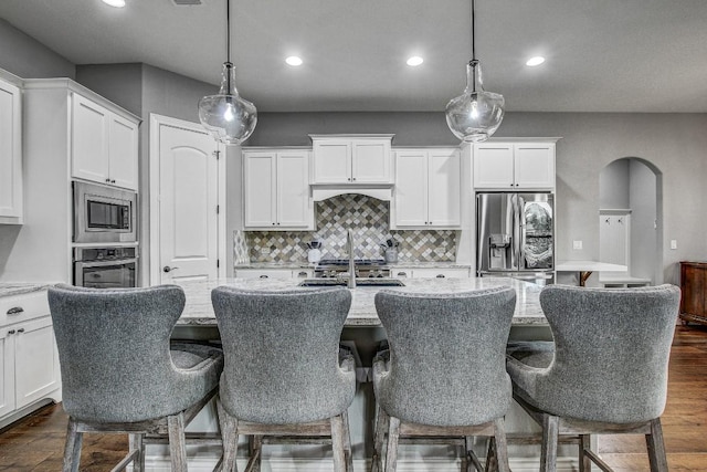 kitchen with a kitchen island with sink, backsplash, stainless steel appliances, recessed lighting, and white cabinetry