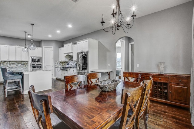 dining room featuring an inviting chandelier, arched walkways, recessed lighting, and dark wood-type flooring