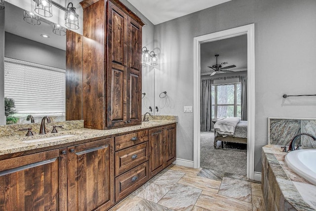 full bath featuring connected bathroom, double vanity, baseboards, and a sink