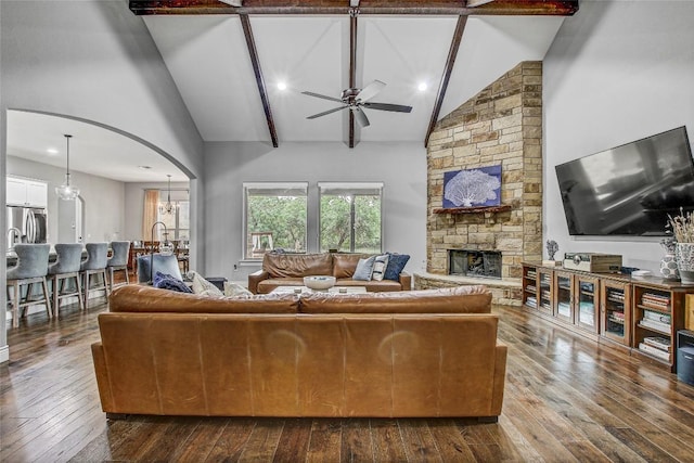 living area with a ceiling fan, arched walkways, a fireplace, high vaulted ceiling, and dark wood-style floors