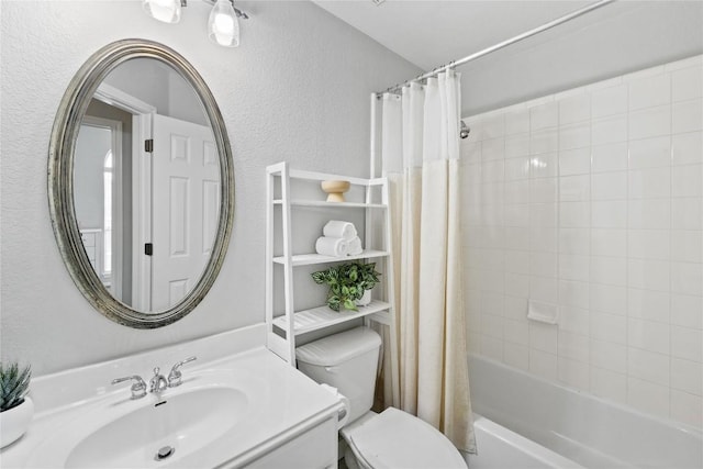 full bath with vanity, a textured wall, shower / bath combo, and toilet
