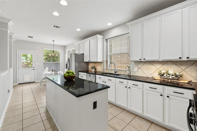 kitchen with a kitchen island, white dishwasher, stainless steel refrigerator with ice dispenser, a sink, and light tile patterned floors