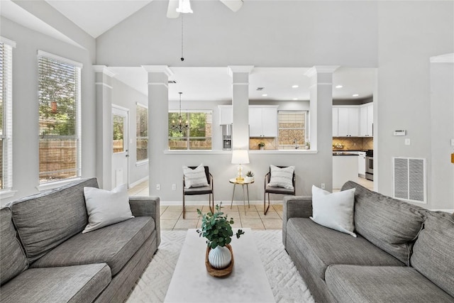 living room with visible vents, light tile patterned flooring, baseboards, ornate columns, and ceiling fan with notable chandelier