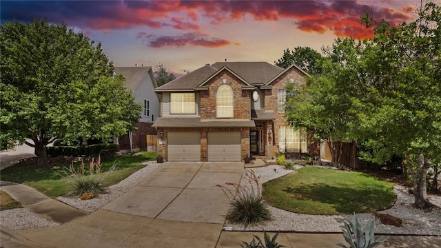traditional-style house featuring a garage, a lawn, concrete driveway, and brick siding