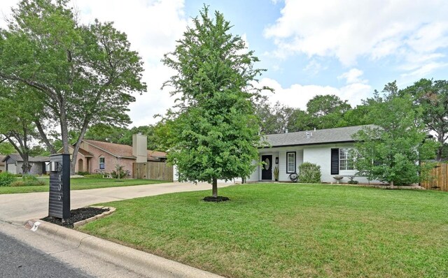 ranch-style home with fence, driveway, and a front lawn