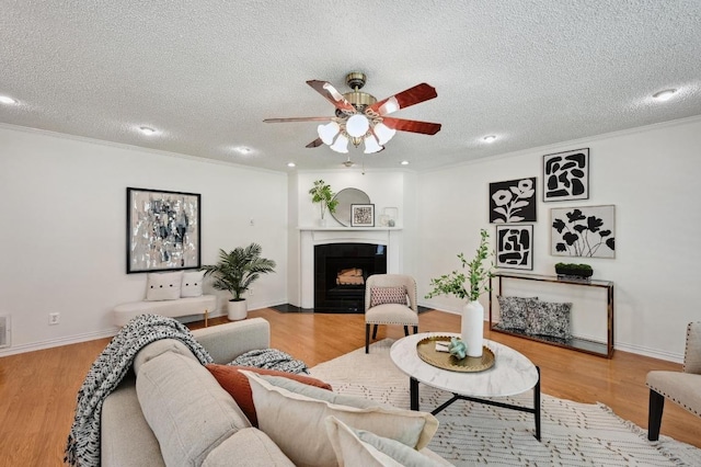 living room featuring a fireplace with flush hearth, a textured ceiling, ceiling fan, and wood finished floors