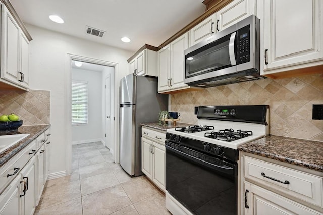 kitchen featuring backsplash, visible vents, light tile patterned floors, dark stone counters, and stainless steel appliances