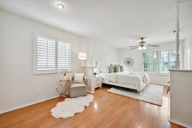 bedroom with baseboards, a textured ceiling, wood finished floors, and visible vents