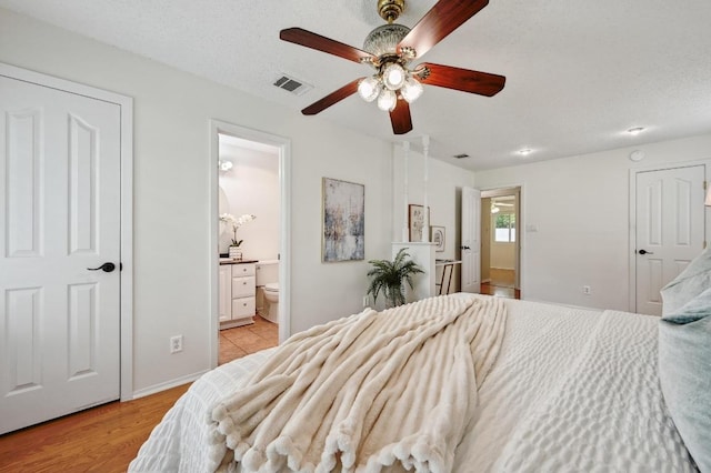 bedroom with ensuite bath, baseboards, visible vents, and light wood-style floors