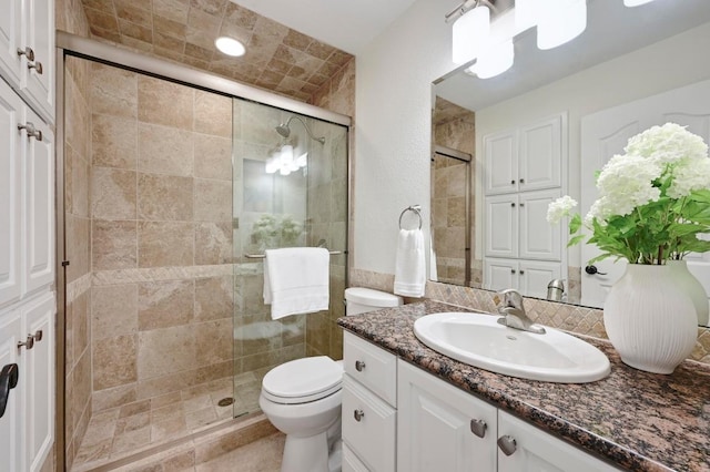 full bathroom featuring vanity, a stall shower, and toilet