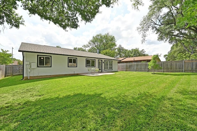 rear view of house featuring a lawn, a fenced backyard, and a patio
