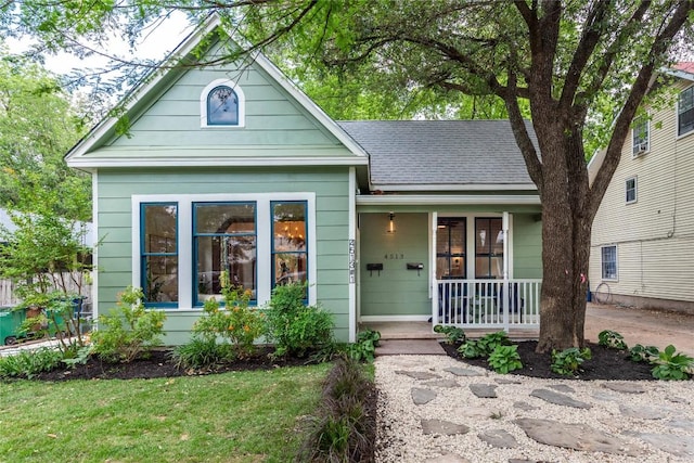 view of front of house featuring a porch, roof with shingles, and a front lawn