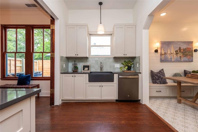 kitchen featuring stainless steel dishwasher, a sink, dark wood-style flooring, and dark countertops