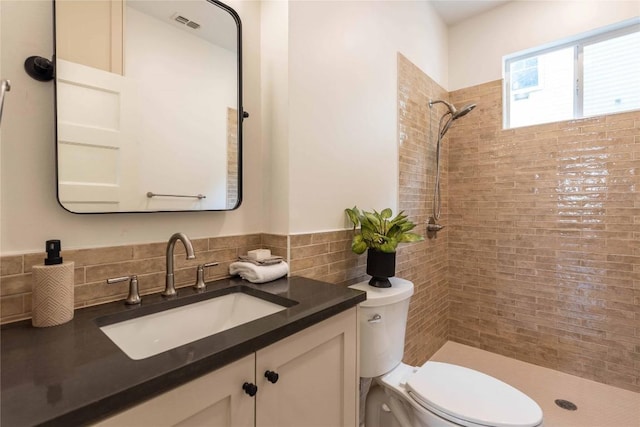 bathroom featuring visible vents, tile walls, vanity, toilet, and tiled shower
