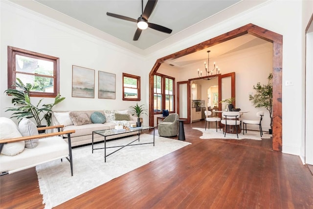 living room featuring a healthy amount of sunlight, ornamental molding, ceiling fan with notable chandelier, and wood finished floors