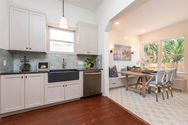 kitchen featuring dark countertops, a sink, dark wood-type flooring, and dishwasher